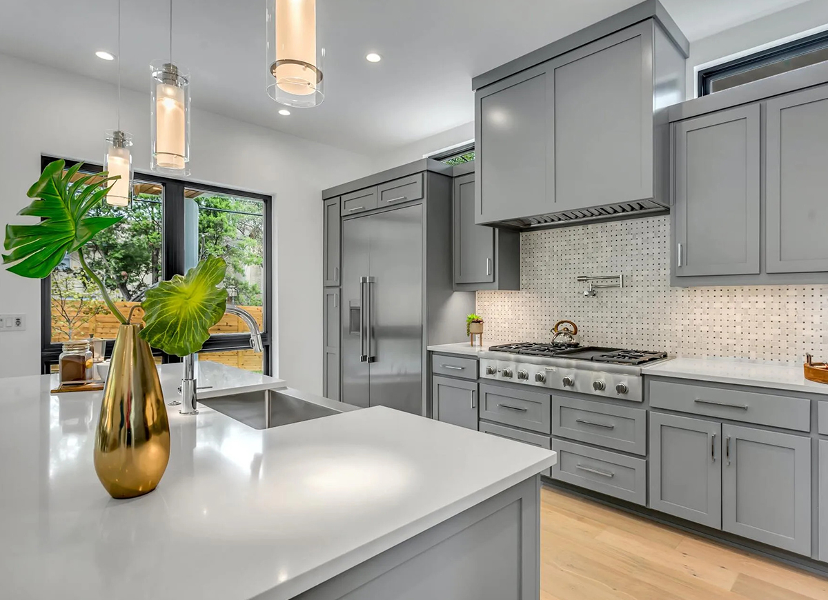 A kitchen with grey cabinets and white counters.