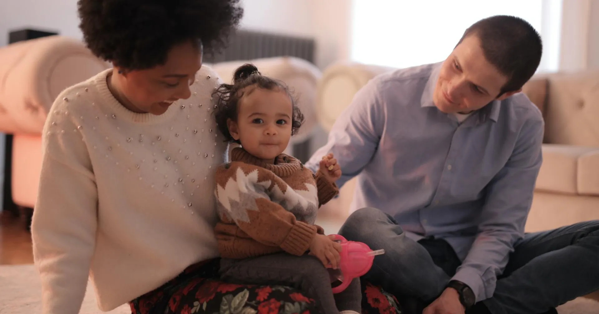 A woman and two men sitting on the couch with a child.